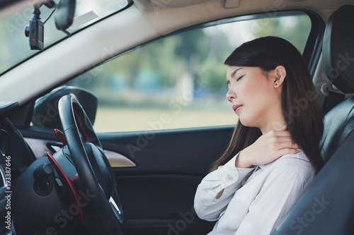Asian businesswoman having pain on her shoulder and neck while driving