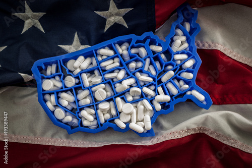 Healthcare, opioid epidemic and drug abuse concept with the map of USA filled with oxycodone and hydrocodone pharmaceutical pills on the American flag photo