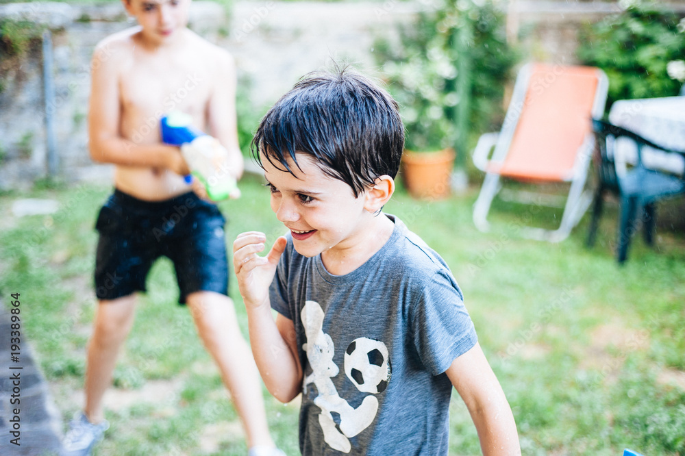 children play in the garden with guns and water rifles on a sunny summer day children play in the garden with guns and water rifles on a sunny summer day