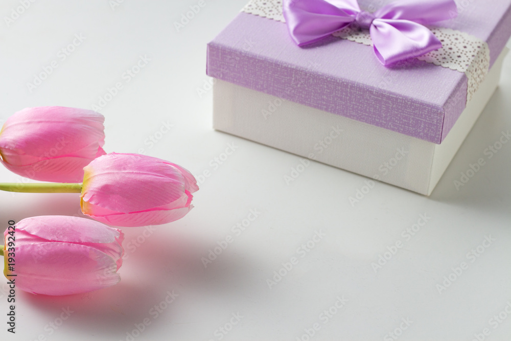 Three Pink Tulips and a Gift Box On The White Background. Artificial flowers. Copy space Three Pink Tulips and a Gift Box On The White Background. Artificial flowers. Copy space