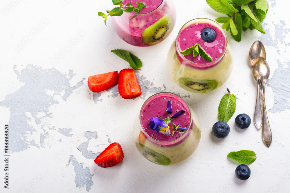 Colorful detox layered smoothie with natural edible flowers, berries and mint Colorful detox layered smoothie with natural edible flowers, berries and mint