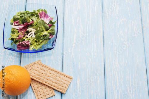 Fresh green leaves of vegetables arugula, salad, on a wooden table. Bright orange and bread photo