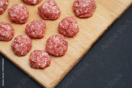 Meat Raw Balls from Raw Beef force-meat on a Chopping board. close Up. Food Preparing. Cooking. Dark Background.
