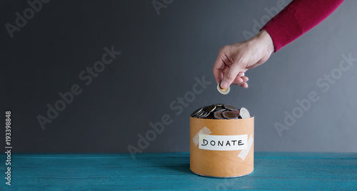 Donation Concept. Hand putting Money Coin into a Donate Box
