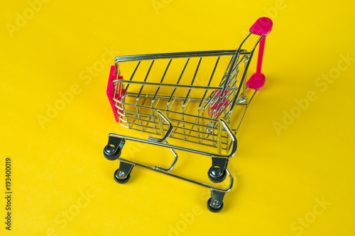 Shopping cart or supermarket trolley on yellow background, business finance shopping concept.