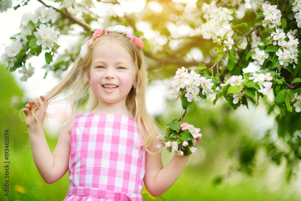 Adorable little girl in blooming apple tree garden on beautiful spring day Adorable little girl in blooming apple tree garden on beautiful spring day