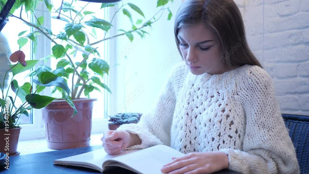 Young Woman Reading Book While Sitting in Office Young Woman Reading Book While Sitting in Office
