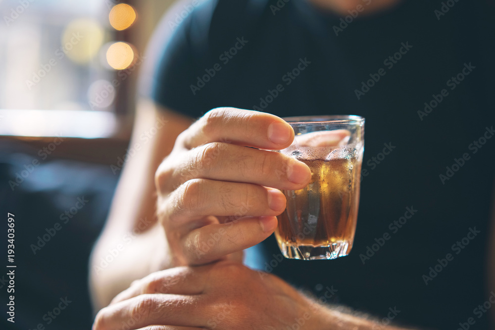 The man is holding ice tea in his hand. A refreshing drink. Close-up The man is holding ice tea in his hand. A refreshing drink. Close-up