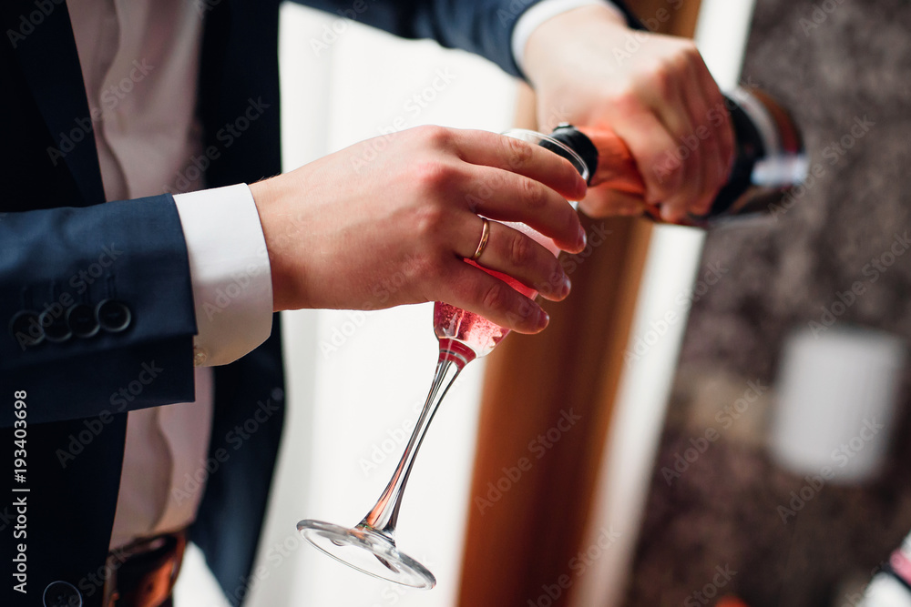 groom pours red champagne from a bottle into a close-up glass groom pours red champagne from a bottle into a close-up glass