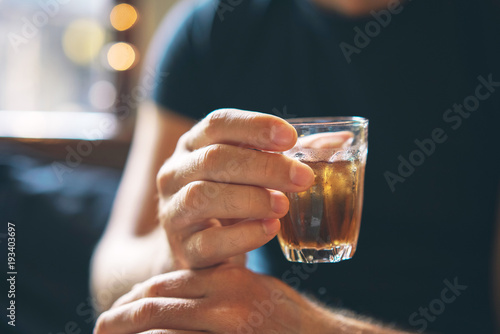 The man is holding ice tea in his hand. A refreshing drink. Close-up