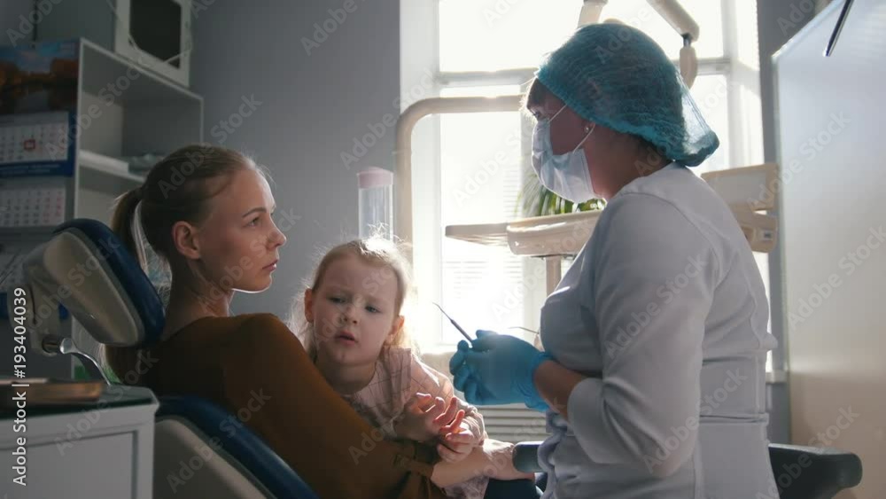 Girl, her mom and the dentist in the dental office, the stomatologist consulting with a special toy Girl, her mom and the dentist in the dental office, the stomatologist consulting with a special toy