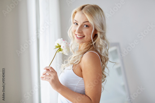 woman in underwear smelling flower at window