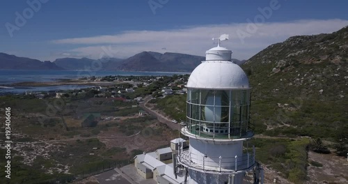 4K high quality aerial video sunny day view of historical Slangkop lighthouse built in 1914 and Kommetjie town in the background near beach at sea shore in Western Cape near Cape Town, South Africa photo