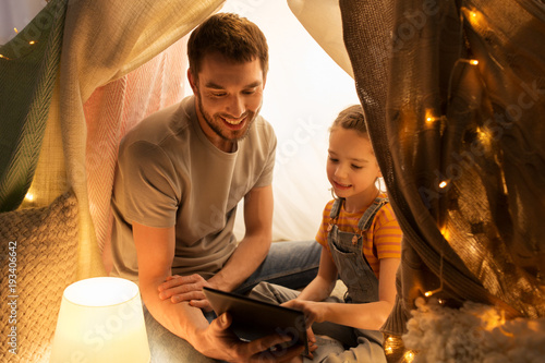 family with tablet pc in kids tent at home