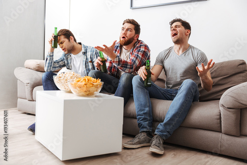 Canvas Print Portrait of three disappointed young men watching football