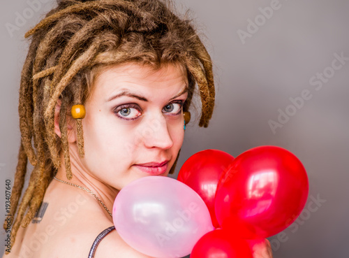 european woman with dreadlocks in gray dress with balloons on grey background © dark_blade