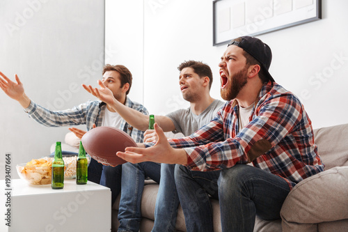 Photography Portrait of three upset young men watching american football