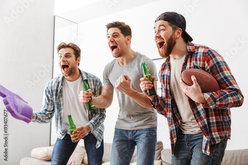 Sticker Portrait of three happy young men watching american football
