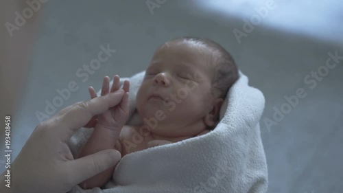 Cute little newborn baby lying in the blanket and holding mother's finger
