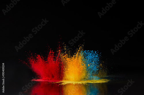 red, blue and yellow holi powder explosion on black, Hindu spring festival