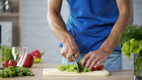 Husband cutting fresh salad on board for healthy family lunch, cooking help