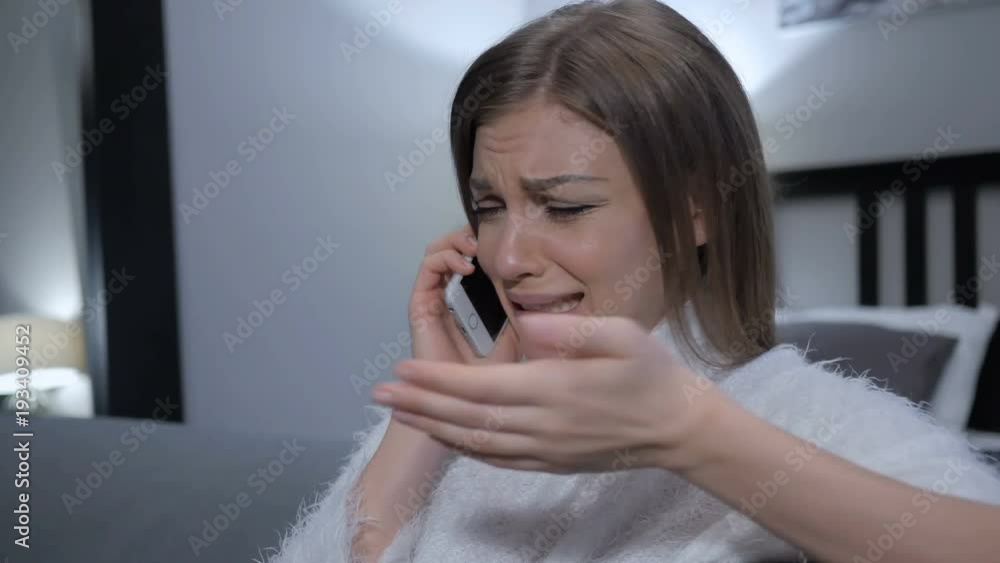 Crying Woman Talking on Phone, While Sitting on Couch Crying Woman Talking on Phone, While Sitting on Couch