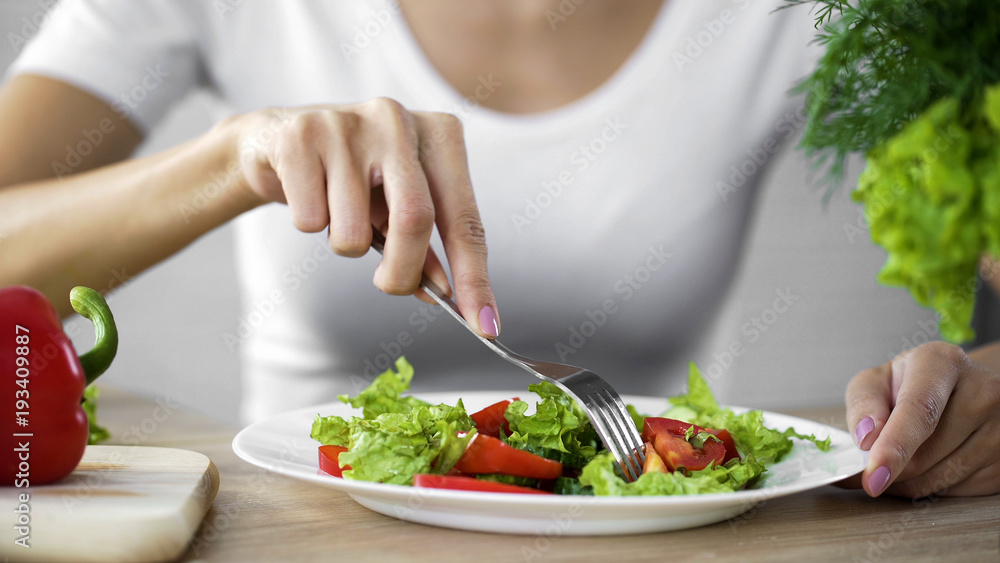 Young lady taking tomato salad fork from dinner plate, healthy snack, vitamins