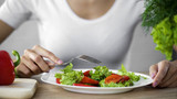Woman sitting at the table with salad plate, healthy nutrition, energy support