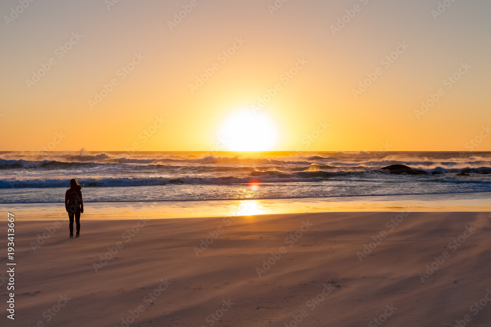 Silhouette girl watching a sunset on a sandy beach with rough ocean wind Silhouette girl watching a sunset on a sandy beach with rough ocean wind