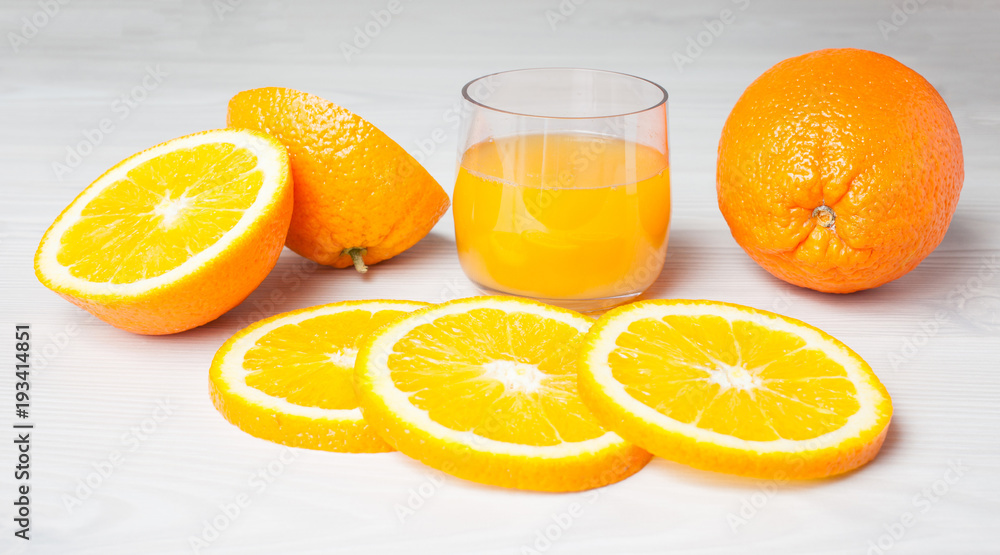 Orange juice glass with orange slices on a light wood background Orange juice glass with orange slices on a light wood background