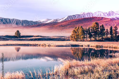 Mirror surface of the lake in the mountain valley. The peaks of the cliffs on the horizon at the colorful sky. Autumn weather