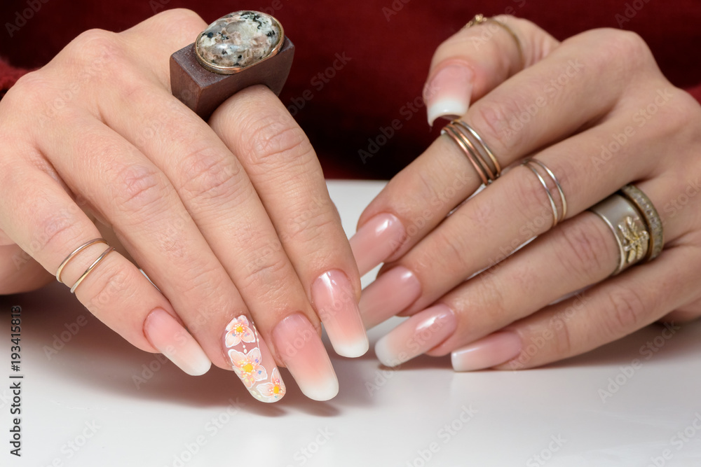 Female hands with manicure close up. Drawing of a branch with orange flowers. It is isolated on a white background. Female hands with manicure close up. Drawing of a branch with orange flowers. It is isolated on a white background.