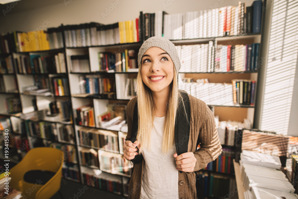 Portrait view of a gorgeous cheerful blond high school student girl standing in the school library. Portrait view of a gorgeous cheerful blond high school student girl standing in the school library.