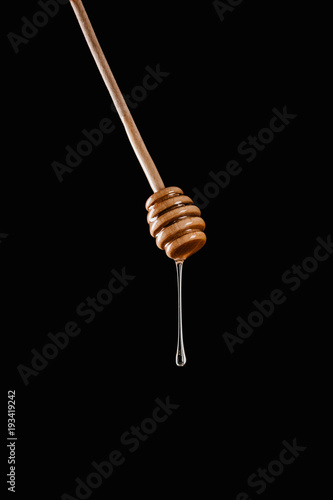 honey dripping from honey stick isolated on black