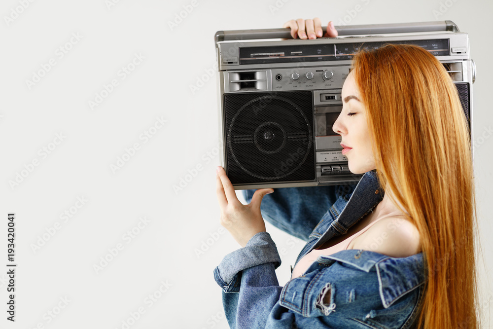 beautiful red-haired woman in a denim jacket holding retro tape recorder on  a white background Stock Photo | Adobe Stock