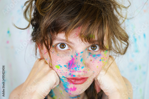 Mujer joven con manchas de pintura de colores en la cara 