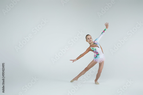 Rhythmic gymnastics caucasian blonde girl in gown for performances athlete exercises showing flexibility stretching  and acrobat balance on white background isolated