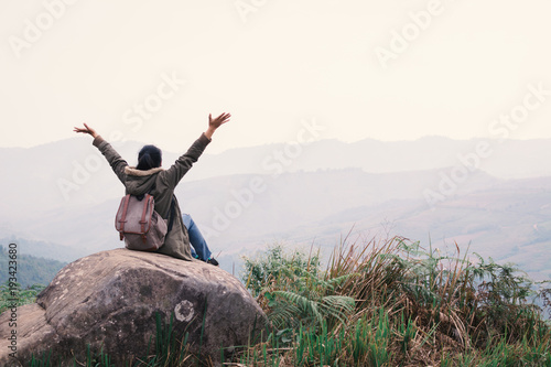 Happy woman feeling exciting sitting on rock open hands on top hill , Relax time on holiday travel concept,selective and soft focus,color of hipster style