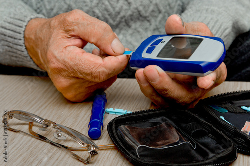 Concept diabetes in the elderly retired. Senior man with glucometer checking blood sugar level at home. Learn to use a glucometer