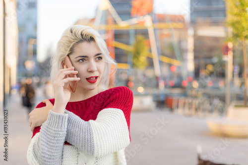Portrait of cheerful young woman talking on smartphone outdoors.