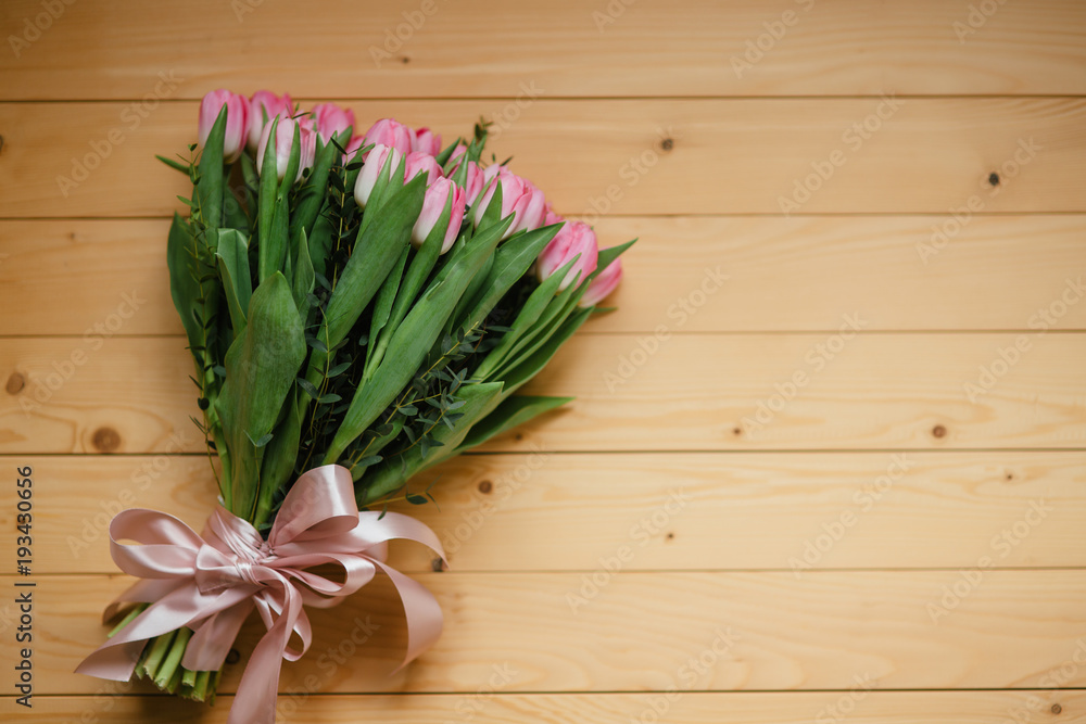 Bouquet of pink tulips and perfume with a beautiful bow on a wooden background Bouquet of pink tulips and perfume with a beautiful bow on a wooden background