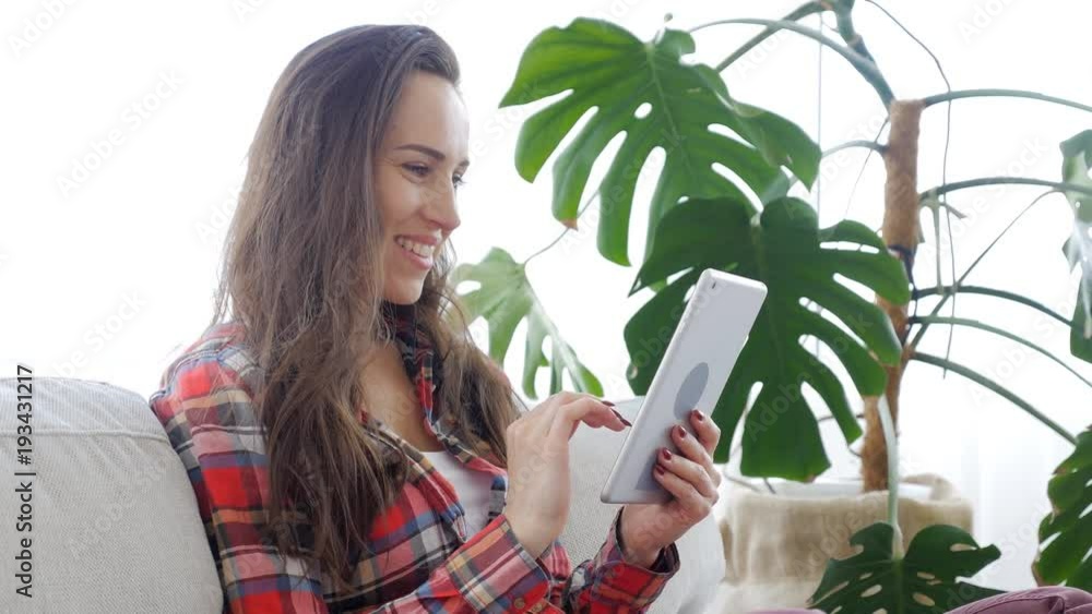 Woman sitting on sofa and using tablet Woman sitting on sofa and using tablet