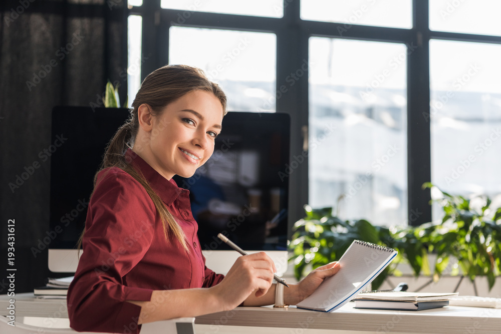 happy young businesswoman making notes at workplace happy young businesswoman making notes at workplace