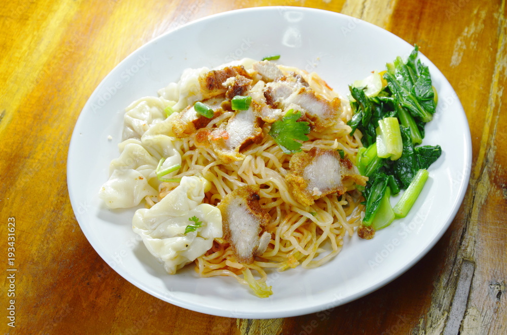 dry Chinese egg noodles topping crispy pork and dumpling on plate dry Chinese egg noodles topping crispy pork and dumpling on plate