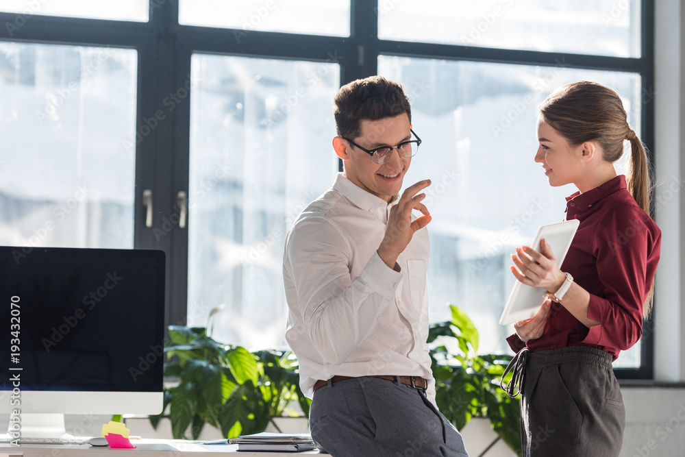 young businessman showing okay sign to his colleague with tablet young businessman showing okay sign to his colleague with tablet
