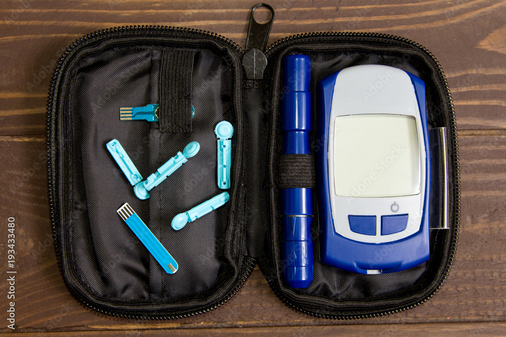 Glucometer with lancet pen and test strip lies in case bag on the wooden  background. Diabetes Stock Photo | Adobe Stock