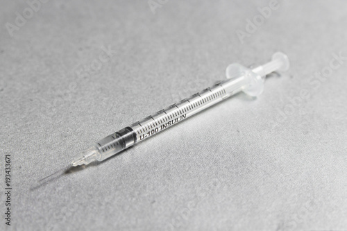 A syringe with insulin inscription on a silver background. The concept of diabetes