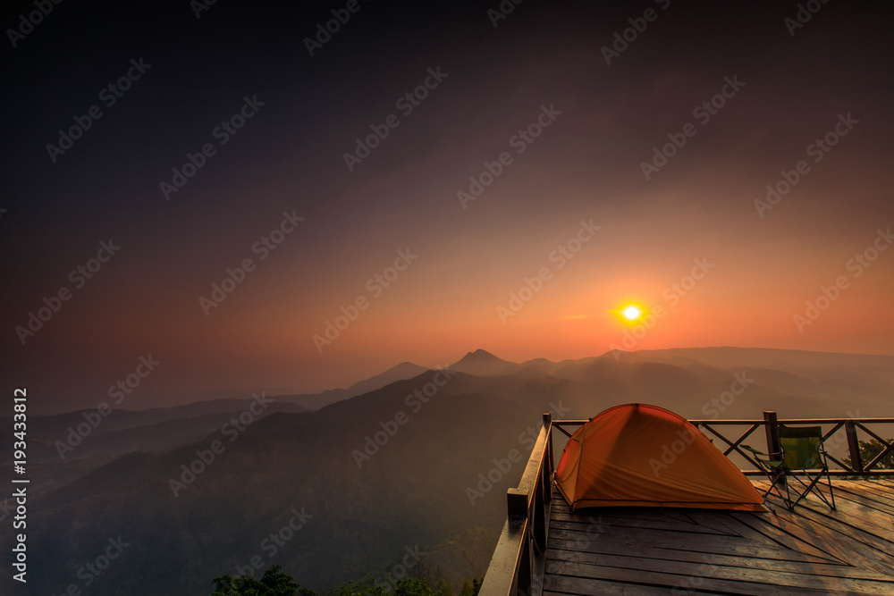 The orange hiker's  tent on the wooden terrace in  high mountain.