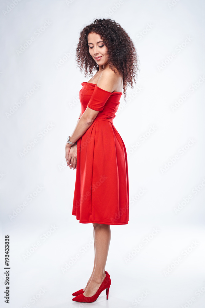 Beautiful curly female in red dress and red high heels shoes in full length Beautiful curly female in red dress and red high heels shoes in full length