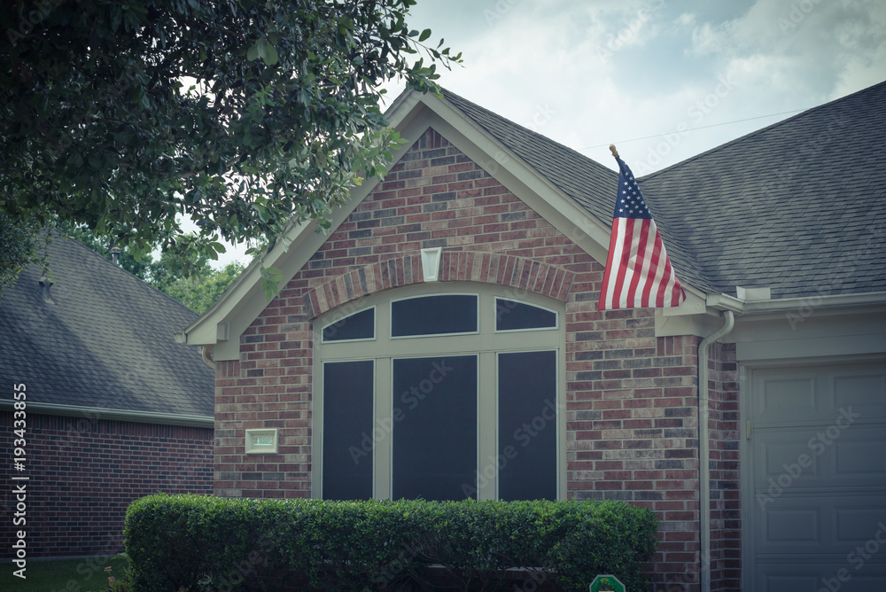 Fototapeta premium Ganek frontowy typowego domu jednopiętrowego dumnie wyświetlającego amerykańską flagę. Vintage ton